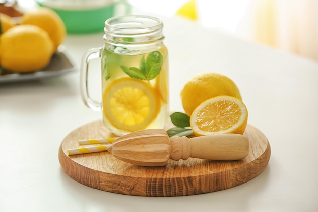 Tavola di legno con spremiagrumi e limonata sul tavolo bianco