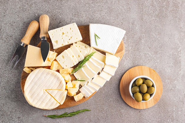 Tavola di legno con vari formaggi e olive Brie Camembert Parmigiano feta formaggio blu