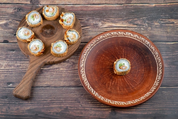 Tavola di legno di rotoli di sushi tempura posizionati sul tavolo di legno.