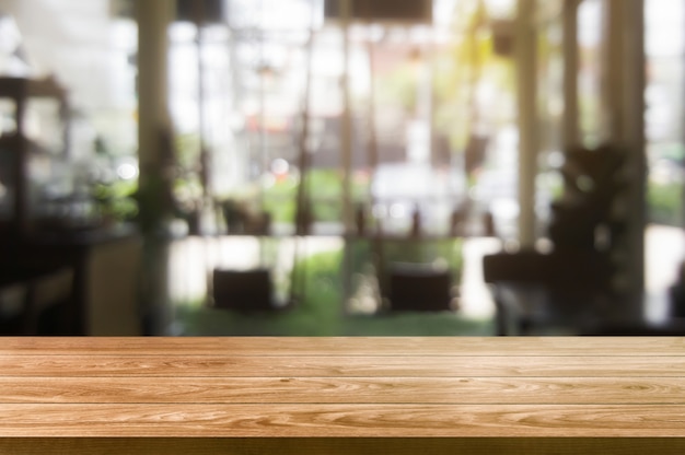 Tavola di legno nel fondo della sfuocatura del ristorante moderno