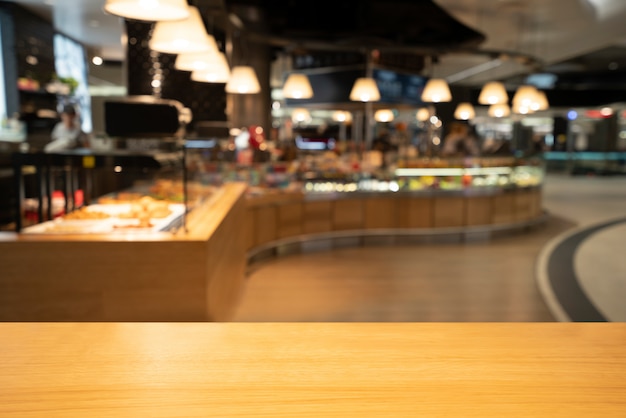 Tavola di legno nel fondo della sfuocatura del ristorante moderno