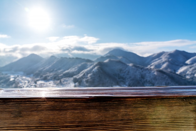 Tavola di legno vuota del bordo davanti alla vista vaga della montagna della neve