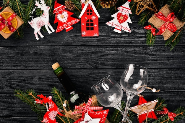 Tavola di Natale che serve e una bottiglia di vino Decorazioni per l'albero di Natale e l'albero di Natale di Capodanno su uno sfondo di legno Spazio libero per il testo