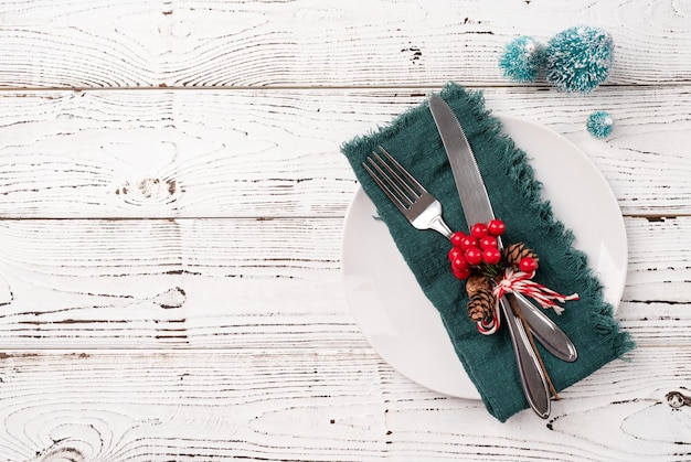 Tavola di Natale con posate bianche e decorazioni rosse e verdi su fondo di legno bianco Vista dall'alto