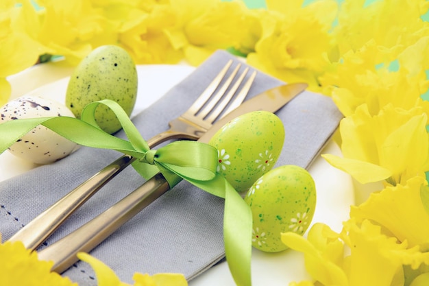 Tavola di Pasqua Tovagliolo di fiori gialli di primavera e posate dorate su piatti bianchi