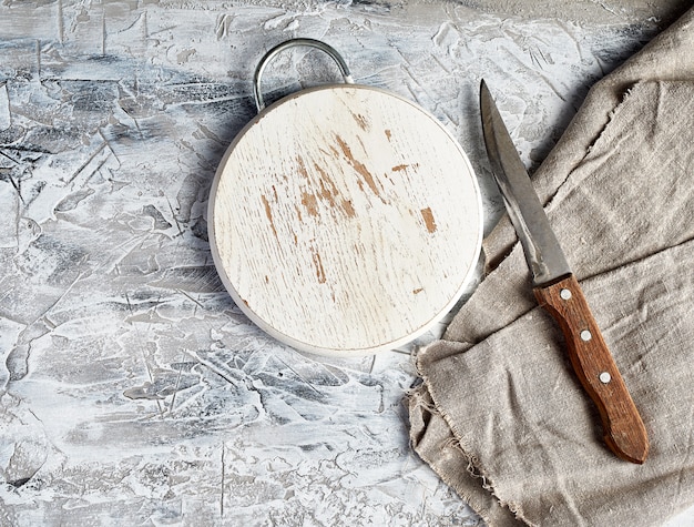 Tavola rotonda di legno vuota, coltello e asciugamano da cucina grigio