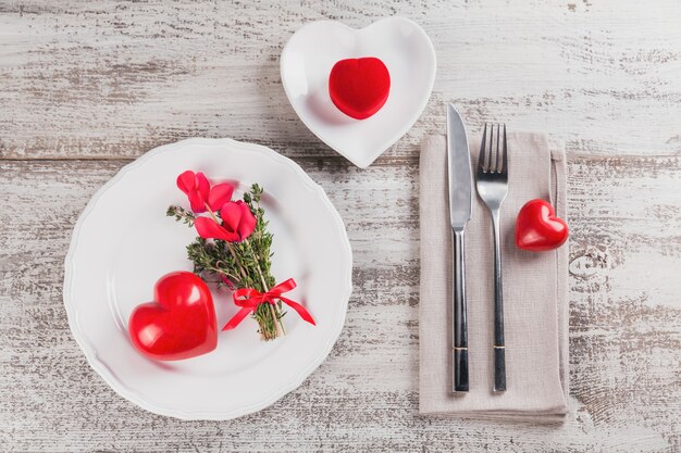 Tavola rustica con fiori di timo e ciclamino e decorazione a forma di cuore su tavola di legno chiaro con copyspace