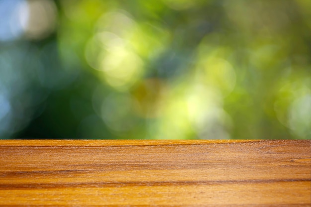 Tavola vuota del bordo di legno davanti al fondo verde del bokeh per la visualizzazione del prodotto