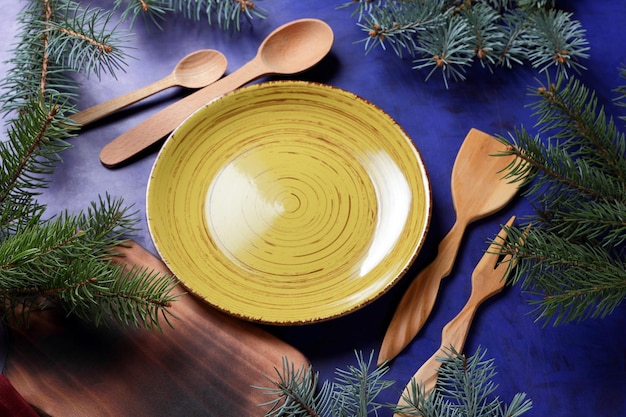 Tavole di legno elettrodomestici da cucina in legno un tovagliolo rosso un piatto giallo e rami di abete su sfondo blu Vista dall'alto