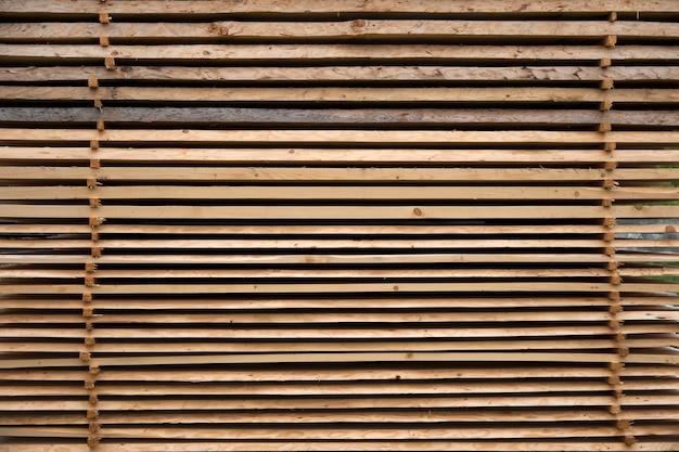 Tavole di legno grezzo impilate all'aria aperta per l'asciugatura come sfondo