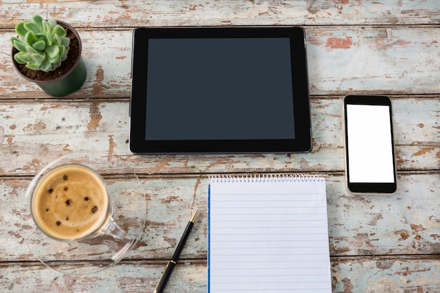 Tavoletta digitale con smartphone, pianta da vaso, penna, blocco note e tazza di caffè