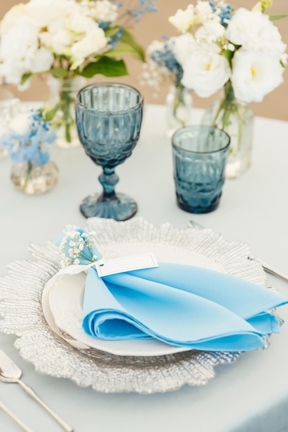 Tavoli da matrimonio per gli ospiti con tovaglia blu decorata con bicchieri e fiori premium