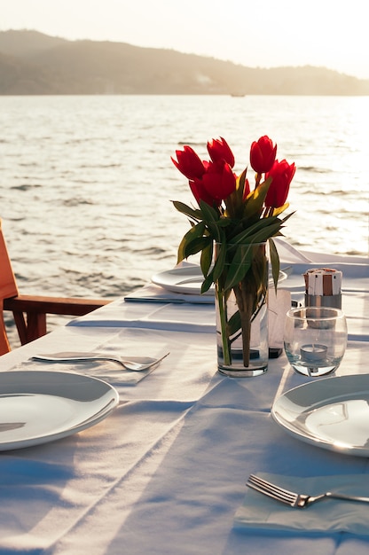 Tavolo apparecchiato con fiori al ristorante sulla spiaggia