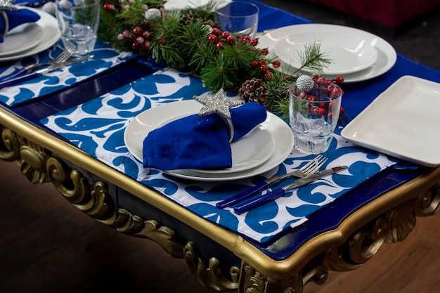 Tavolo con decoro natalizio blu con stoviglie e bicchieri per la cena di natale