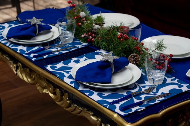 Tavolo con decoro natalizio blu con stoviglie e bicchieri per la cena di natale