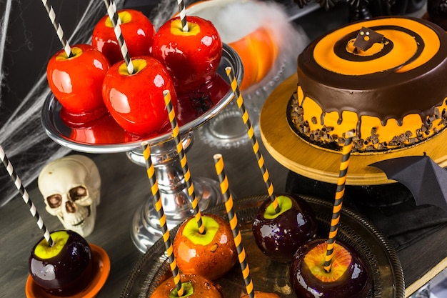 Tavolo con mele caramellate colorate e torta per la festa di Halloween.