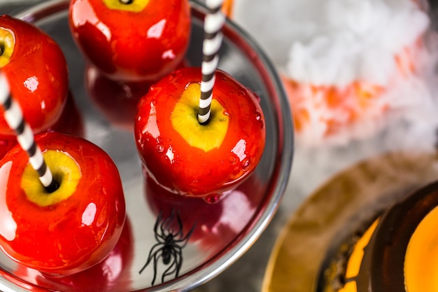 Tavolo con mele caramellate colorate e torta per la festa di Halloween.