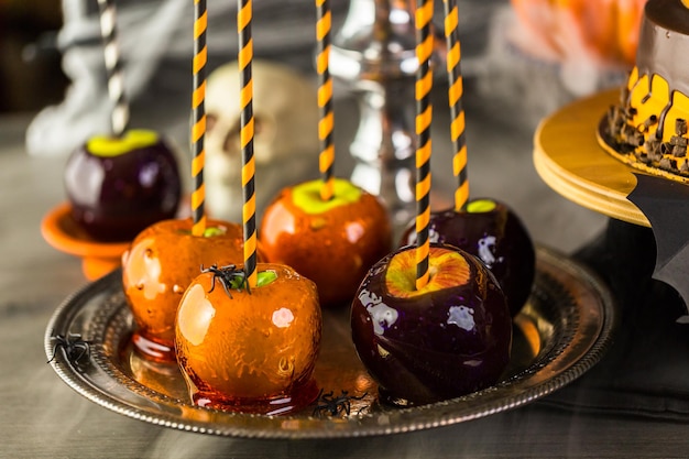 Tavolo con mele caramellate colorate e torta per la festa di Halloween.