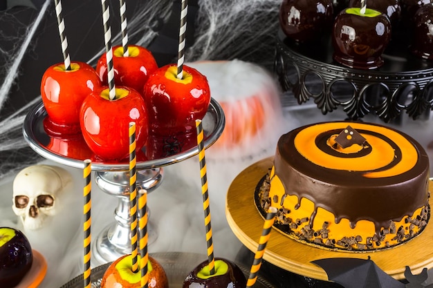 Tavolo con mele caramellate colorate e torta per la festa di Halloween.