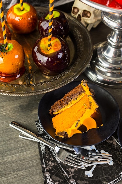 Tavolo con mele caramellate colorate e torta per la festa di Halloween.