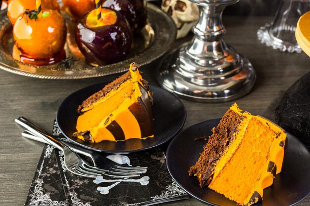 Tavolo con mele caramellate colorate e torta per la festa di Halloween.