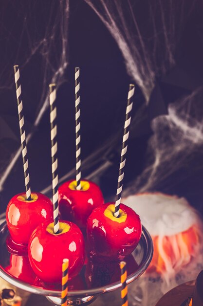 Tavolo con mele caramellate colorate e torta per la festa di Halloween.