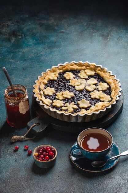 Tavolo con torta calda ai frutti di bosco, tazze calde con tè al limone e marmellata