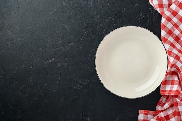 Tavolo da cucina con piatto vuoto colore bianco, tovaglia rossa e spazio per la tua ricetta o menu.