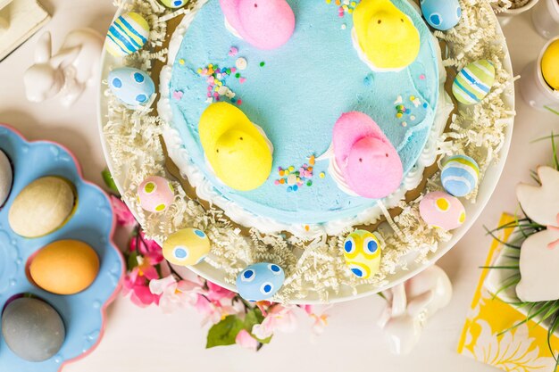 Tavolo da dessert con torta pasquale decorata con i tradizionali pulcini di marshmallow pasquali.