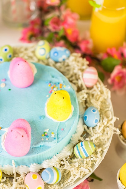 Tavolo da dessert con torta pasquale decorata con i tradizionali pulcini di marshmallow pasquali.