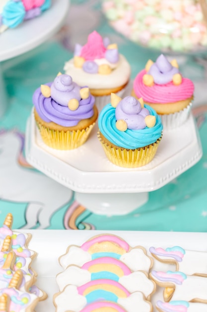 Tavolo da festa di compleanno per bambina con torta di unicorno, cupcakes e biscotti zuccherati.