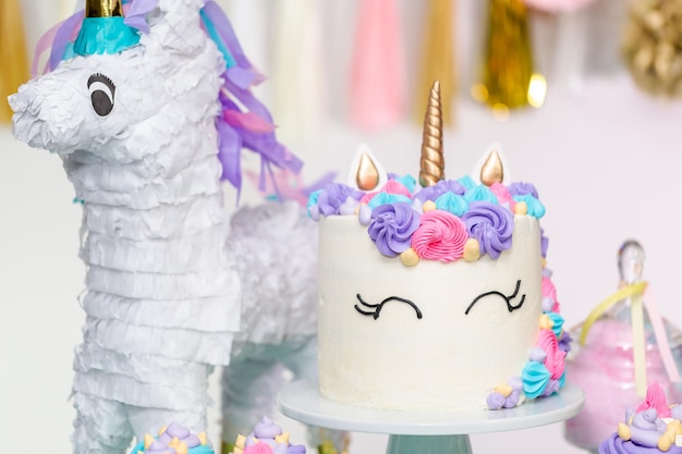 Tavolo da festa di compleanno per bambina con torta di unicorno, cupcakes e biscotti zuccherati.