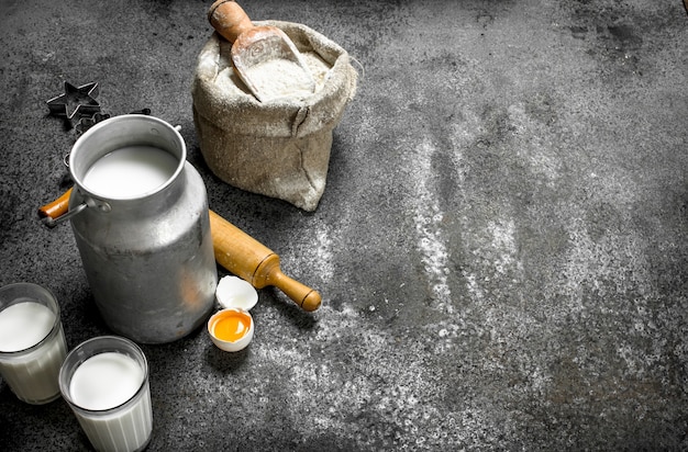 Tavolo da forno. Latte, farina e altri ingredienti per la pasta. Su un tavolo rustico.