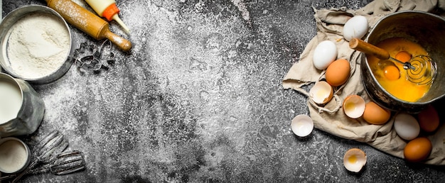 Tavolo da forno. Sbattere le uova nella vecchia ciotola. Sulla tavola rustica.