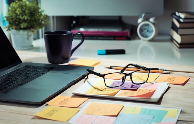 Tavolo da lavoro con computer portatile e blocco note, tazza di caffè al mattino