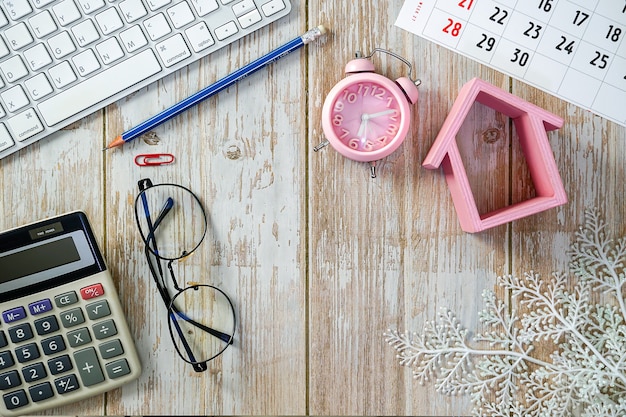 Tavolo da lavoro in legno con tastiera portatile calcolatrice orologio modello casa e forniture Concetto di costo domestico