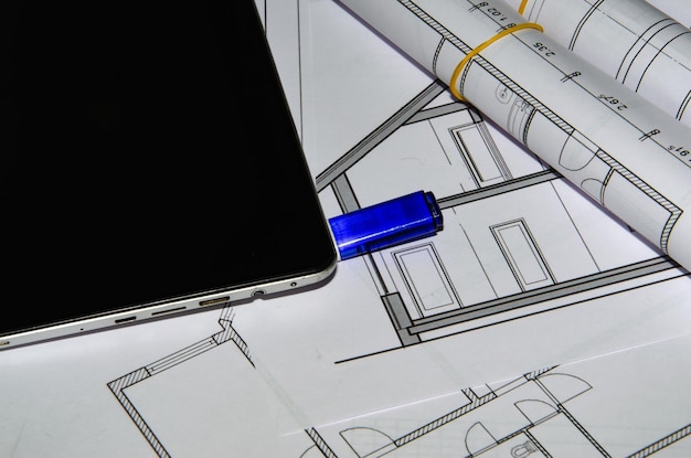 Tavolo da lavoro per architetti con disegni tecnici e tablet.