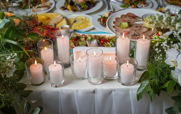 Tavolo da matrimonio con candele tovaglia bianca vari cibi e fiori fuoco selettivo