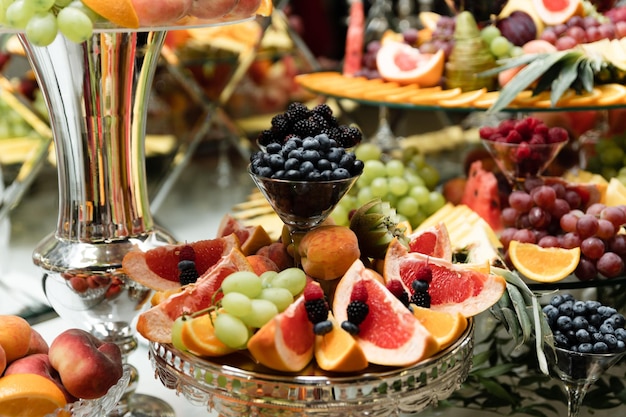 Tavolo da matrimonio con frutta su cui vari frutti esotici e dolci. barretta di cioccolato con frutta. pere, mele, ananas e tanti altri cibi al banchetto