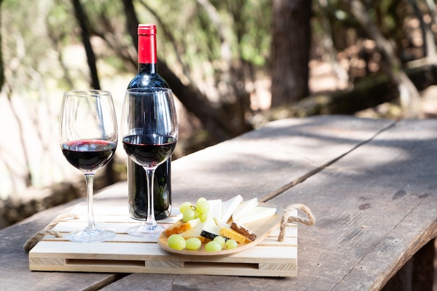 Tavolo da picnic con vino rosso, pane e formaggio con sovrapposizione di ombre