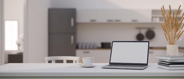 Tavolo da pranzo bianco con laptop notebook e decorazioni su cucina moderna sfocata sullo sfondo