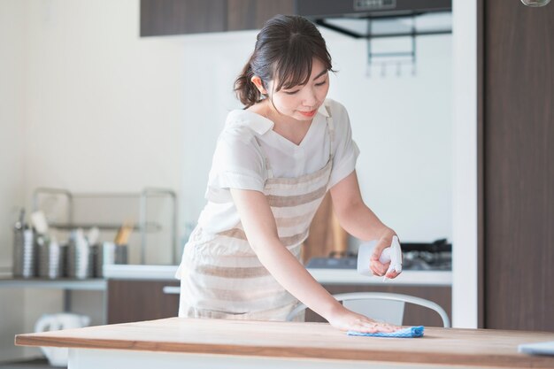 Tavolo da pranzo domestico disinfettante della donna asiatica con spruzzo