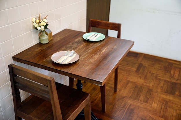 Tavolo da pranzo in legno antico con stoviglie e vaso di fiori nel ristorante