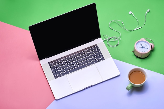 Tavolo da scrivania con laptop, tazza di caffè, cuffie e fotocamera sul tavolo dei colori