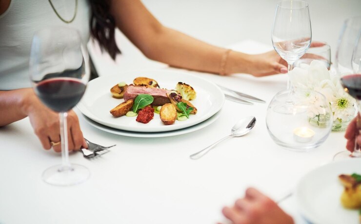 Foto tavolo di coppia e cibo al ristorante in primo piano per l'incollaggio della data di san valentino o il romanticismo nella notte uomo donna e bicchiere di vino rosso con servizio di ristorazione raffinato e mani per cena amore o celebrazione
