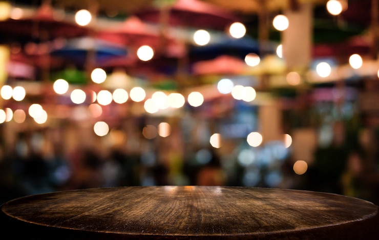 Foto tavolo di legno vuoto di fronte a uno sfondo luminoso festivo astratto sfocato con punti luminosi e bokeh
