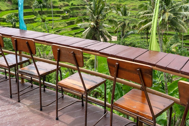 Tavolo e sedie in legno in un caffè tropicale vuoto accanto alle terrazze di riso nell'isola di Bali Indonesia