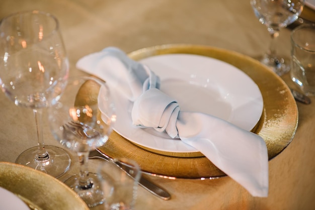 Tavolo festivo a una festa di matrimonio con piatti dorati con tovaglioli bicchieri Banchetto L'elegante tavolo copriva una tovaglia al ristorante che è decorata per gli ospiti