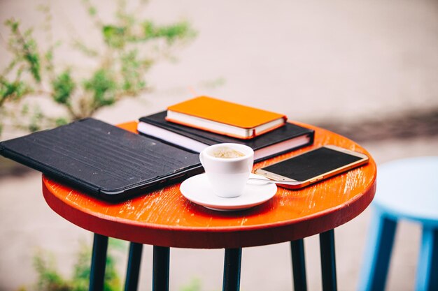 Tavolo in legno all'aperto con taccuino del telefono tablet e tazza di caffè