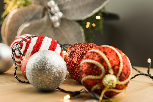 Tavolo in legno con decorazioni natalizie. Palline rosse, argento e oro, scatole regalo, luci, albero di Natale e altro. Messa a fuoco selettiva.
